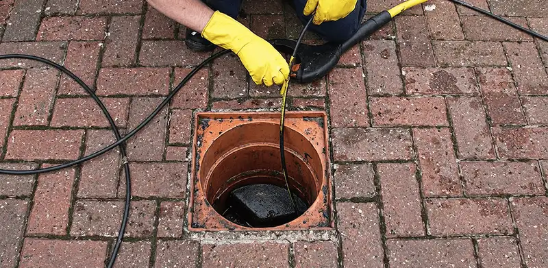 Drain cleaning technician using a drain snake to clear a clogged drain in Phoenix, AZ