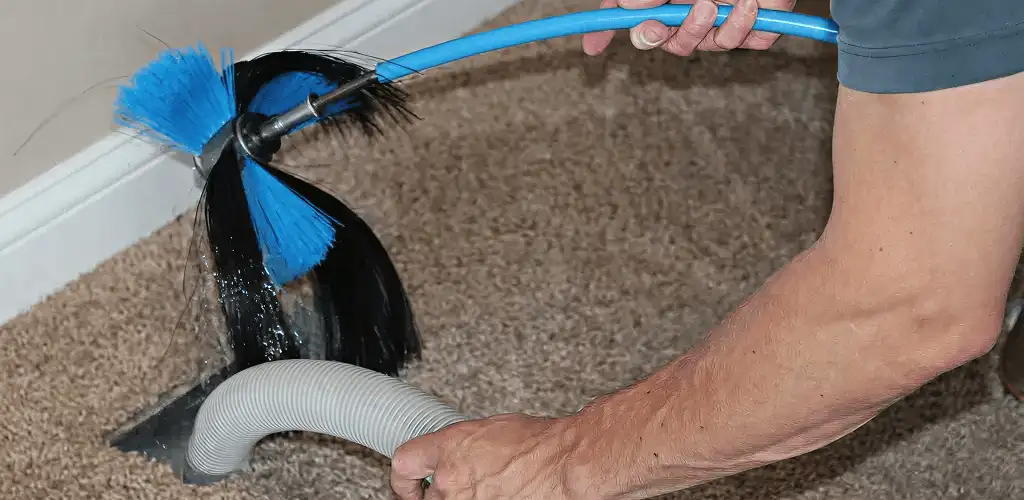 Dryer vent cleaning technician brushing lint from a vent line in Phoenix, AZ